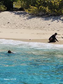 A child enjoys snorkeling in clear waters while an adult relaxes on the beach, showcasing a perfect day of fun and relaxation by the shore.