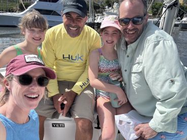 A joyful family poses for a selfie on a boat, capturing a fun day on the water with smiles all around.