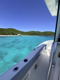 A stunning view from the deck of a boat, showcasing the vibrant turquoise waters and lush green hills in the background — perfect for exploring beautiful coastal destinations.