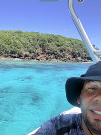 A vibrant selfie captures the stunning turquoise waters and lush greenery of an island backdrop, perfect for showcasing a memorable boating adventure.