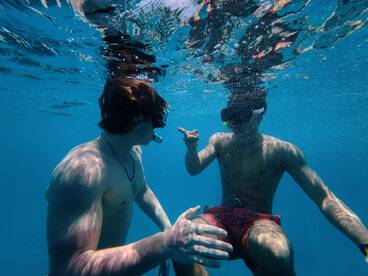 Two friends enjoy snorkeling underwater, capturing the excitement of marine exploration in crystal-clear waters.