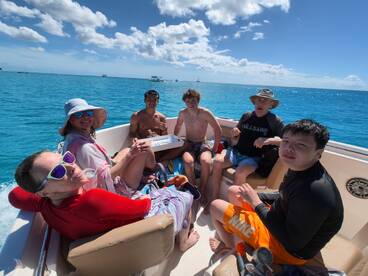 A lively group enjoys a day on the water, relaxing and having fun aboard a boat in stunning turquoise waters — perfect for family adventures and snorkeling trips.
