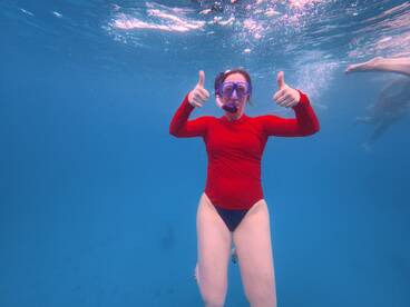 A snorkeler gives a thumbs up underwater, showcasing the excitement of marine adventures — perfect for snorkeling enthusiasts and ocean lovers.