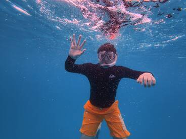 A child enjoys snorkeling underwater, showcasing the vibrant marine life and clear blue waters — a perfect moment for family adventures and aquatic exploration.