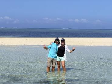 A joyful couple poses in shallow water at a picturesque sandbar, capturing a fun moment during their beach adventure.