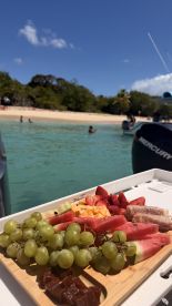 A beautifully arranged platter of fresh fruits and snacks on a boat, perfect for enjoying while anchored at a scenic beach. Ideal for a relaxing day on the water.