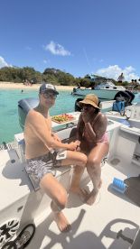 A couple enjoys a relaxing moment on a boat with snacks, surrounded by beautiful beach scenery — perfect for a fun day on the water.