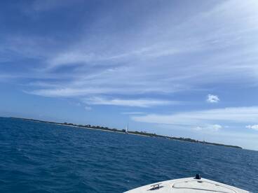 A scenic view of a boat navigating through vibrant blue waters, with a distant shoreline visible under a clear sky — perfect for showcasing boating adventures.