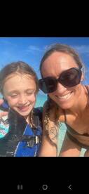 A joyful moment captured as a woman and a child smile for a selfie in shallow water, showcasing the fun and excitement of their day on the water.