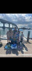 A joyful group of family and friends poses for a photo at the dock after a successful fishing trip, showcasing their excitement and camaraderie.
