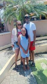 A joyful family poses together in a sunny outdoor setting, capturing a memorable moment during their vacation.