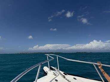A scenic view from the bow of a boat, showcasing vibrant turquoise waters and distant islands — a perfect representation of a day on the water.