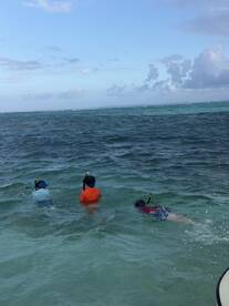 Three children enjoy snorkeling in the clear waters, exploring the vibrant marine life — a perfect family adventure in the ocean.