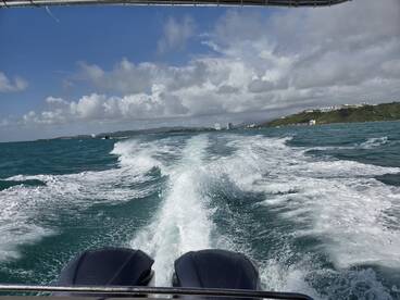 A scenic view from the back of a boat, showcasing the wake and coastline under a bright sky — perfect for capturing the essence of a boating adventure.