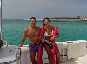 A cheerful couple poses on a boat with snorkeling gear, ready for an adventure in the beautiful turquoise waters — perfect for a fun day of exploration.