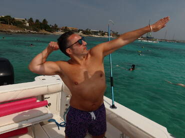 A man flexes his muscles on a boat while enjoying a fun day of snorkeling in clear turquoise waters, capturing the spirit of adventure and celebration.