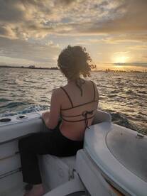 A woman enjoys a serene sunset view from the boat, capturing the essence of relaxation on the water during a picturesque evening.