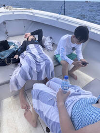 A family enjoys a relaxing moment on a boat, with children lounging and using their phones — a perfect snapshot of leisure time on the water.