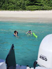 Two friends enjoy snorkeling in the clear turquoise waters near a sandy beach, capturing the essence of a perfect day on the water.