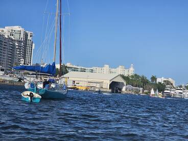 A picturesque sailboat navigates the waters near a marina, showcasing the vibrant atmosphere of boating life.
