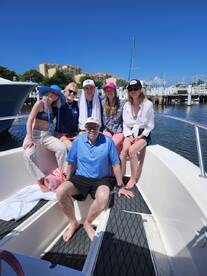 A cheerful group of friends poses on a boat under the bright sun, capturing the essence of a fun day out on the water.