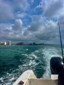 A scenic view from a boat cruising through turquoise waters, showcasing the beautiful coastline and dramatic sky — perfect for capturing the essence of a day on the water.