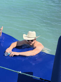 A man relaxes in the water while holding a water bottle, enjoying a sunny day on the boat — perfect for unwinding and soaking up the sun.