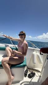 A woman enjoys a refreshing drink while relaxing on a boat under the sun, capturing the essence of a perfect day on the water.