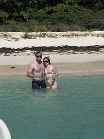 A couple enjoys a refreshing drink while wading in the clear waters of a beautiful beach, perfect for romantic getaways and celebrations.