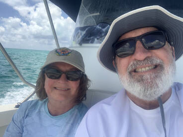 A cheerful couple enjoys a day on the water, capturing a moment of joy aboard their boat with the beautiful ocean in the background.