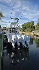 A sleek motorboat docked with multiple outboard engines, showcasing its impressive design and functionality. Ideal for fishing or cruising adventures.