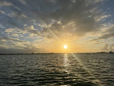 A stunning sunset over tranquil waters, with a silhouette of a boat in the distance — perfect for capturing the serene beauty of a day on the water.