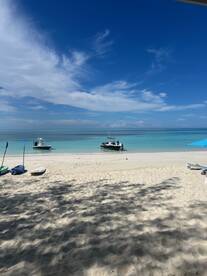 A picturesque beach scene featuring two boats anchored in turquoise waters, perfect for a relaxing day by the shore.