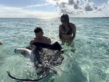 A thrilling encounter as a couple interacts with a stingray in the crystal-clear waters, showcasing the beauty of marine wildlife experiences.