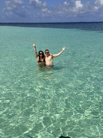 A joyful couple poses in the crystal-clear waters, celebrating their time in paradise — perfect for romantic getaways or fun beach days.