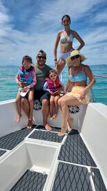 A joyful family poses on the deck of a boat, enjoying a sunny day on the water — perfect for family outings and creating lasting memories.