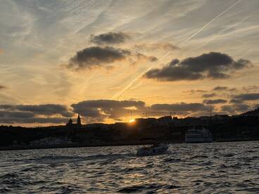 A stunning sunset over the harbor, with silhouettes of boats and buildings creating a picturesque backdrop — perfect for evening cruises and scenic views.