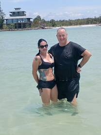 A couple enjoys a refreshing swim in shallow waters, capturing a perfect moment of relaxation and fun at the beach.