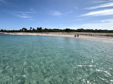 A picturesque beach scene with clear turquoise waters and guests enjoying the serene coastline — perfect for relaxation and beach outings.