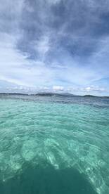 A scenic view of clear turquoise waters under a cloudy sky, capturing the essence of a tranquil marine environment.