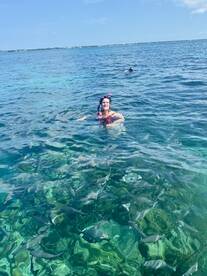 A snorkeler enjoys a vibrant underwater experience surrounded by schools of fish in crystal-clear waters, showcasing the beauty of marine life.