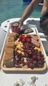 A beautifully arranged platter of snacks including sandwiches, fruits, and drinks, perfect for enjoying on a boat trip.