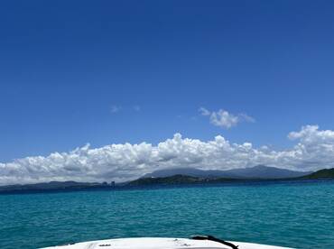 A stunning view of the ocean with vibrant turquoise waters and fluffy clouds under a clear blue sky, showcasing the beauty of a tropical destination.