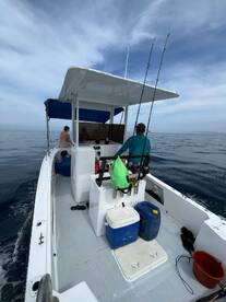 Inside view of a fishing boat's helm area, featuring seating and fishing gear, perfect for a day out on the water.