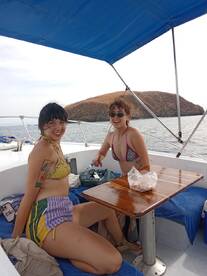 Two friends relax on a boat, enjoying the ocean views in their bikinis — a perfect moment for summer fun and friendship on the water.