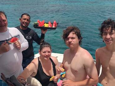A lively group enjoys fresh fruit snacks aboard a boat, capturing the essence of fun and relaxation on the water.