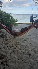 A man relaxes in a hammock on the beach, enjoying the serene ocean view — a perfect spot for unwinding during a tropical getaway.