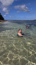Two individuals enjoy a refreshing swim in shallow, crystal-clear waters, perfect for a relaxing beach day or sandbar adventure.