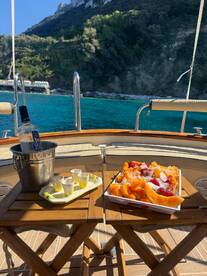 A beautifully arranged platter of fresh fruit and cocktails awaits on a yacht, perfect for enjoying a sunny day on the water.