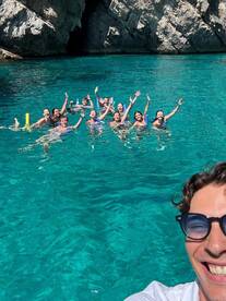 A lively group enjoys a fun day swimming in crystal-clear waters, celebrating together in a picturesque setting.